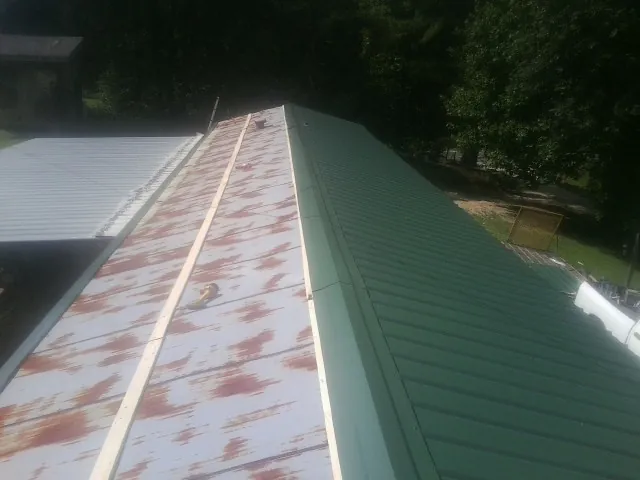Old rusted panels beside newly installed green metal roofing — Wind Damage Roof Repair by Roofing Brothers in Rupert
