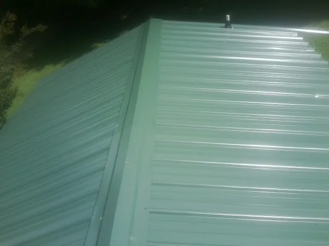 New green metal panels meeting at the ridge of a roof — Flat Roof Repair work by our crew in Rupert