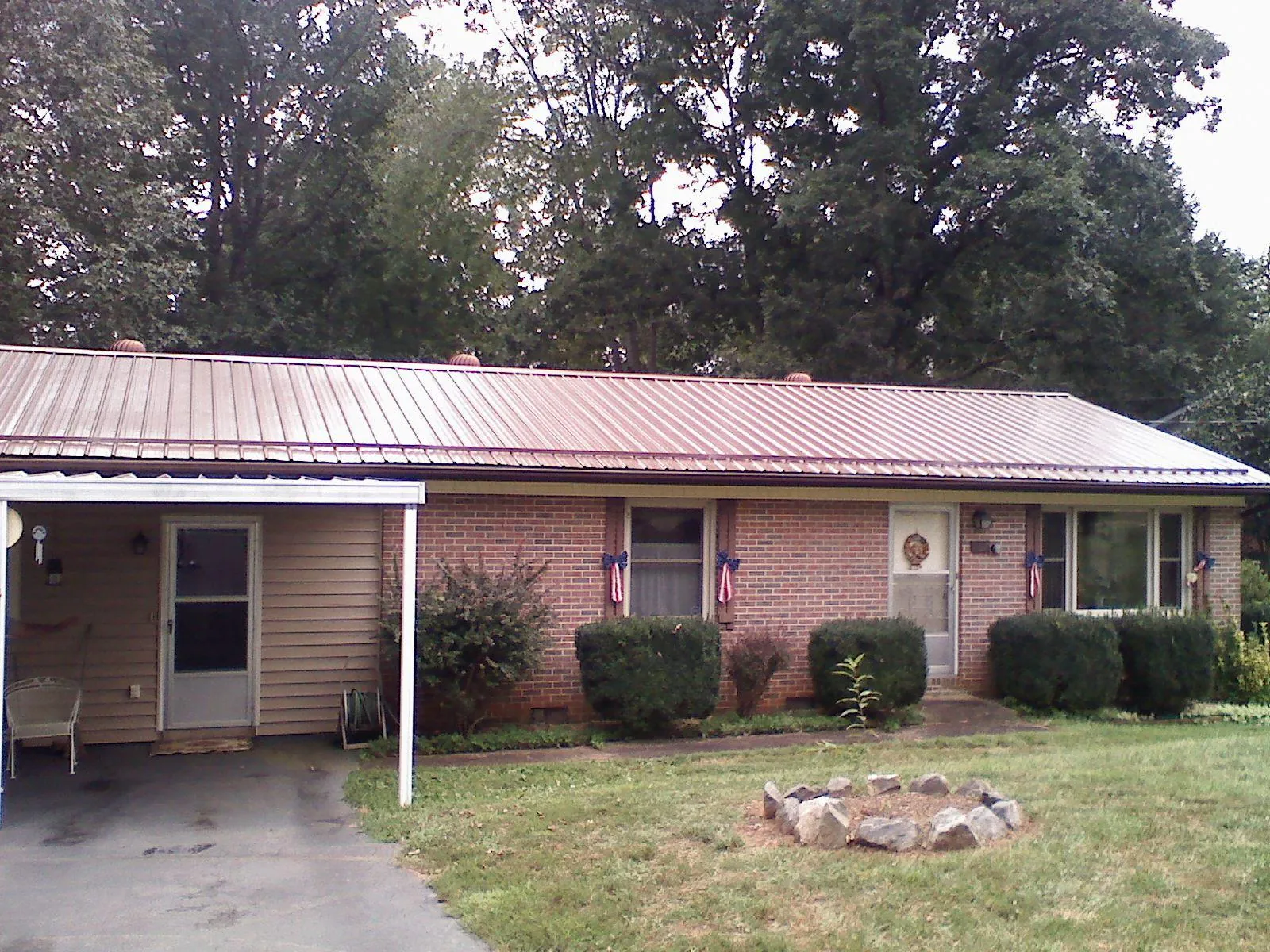 Bronze metal roof and carport on a brick ranch home — Roof Repair work by our crew in Rupert