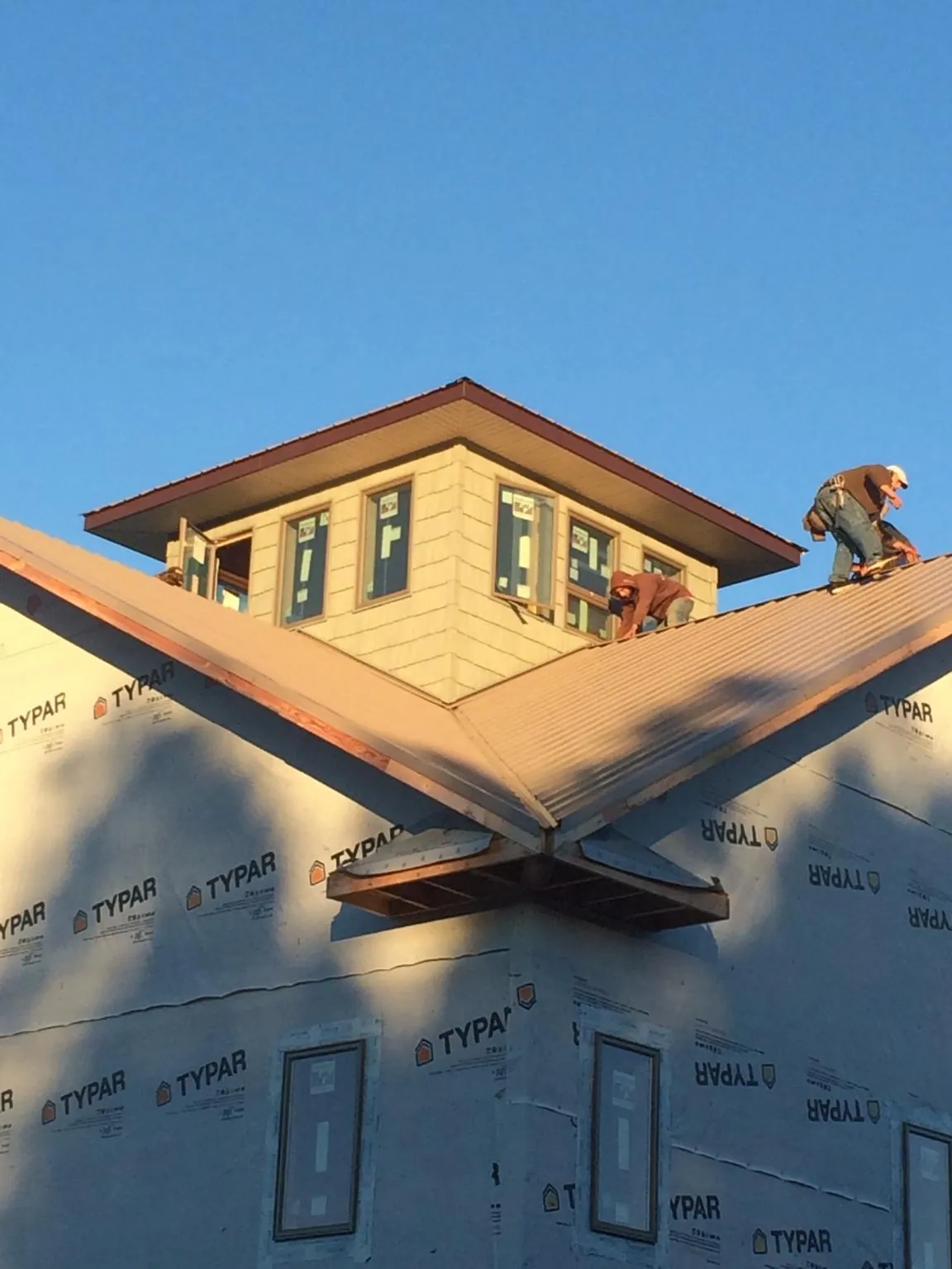 Roofers working around a rooftop cupola on a new metal roof at sunset — Roof Waterproofing in Rupert by Roofing Brothers